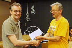 Henk van Gool (links) ontvangt van wedstrijdleider Geert Hovens de eerste prijs in de A-groep van het zomersnelschaaktoernooi op donderdag 2 augustus 2018