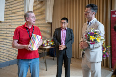 20250712 NK Venlo. Gerard in ’t Veld (links) geeft Loek van Wely een Venloos souvenir: Venloos Köpke. In het midden KNSB-directeur Dharma Tjiam. (Foto Frans Peeters)
