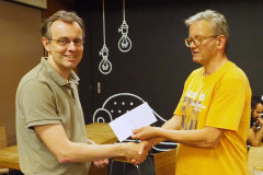 Henk van Gool (links) ontvangt van wedstrijdleider Geert Hovens de eerste prijs in de A-groep van het zomersnelschaaktoernooi op donderdag 2 augustus 2018