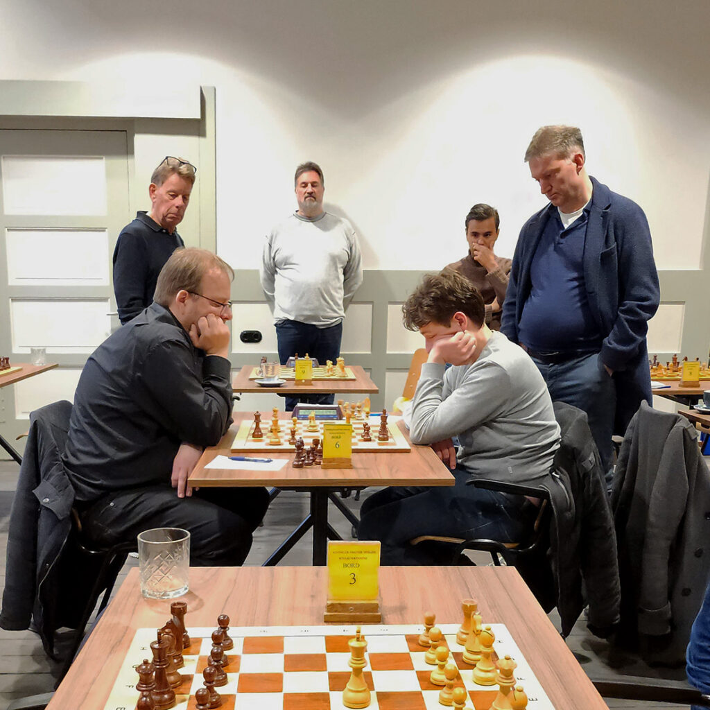 KNSB-wedstrijd Venlo1 tegen Vianen/DVP 1. Bord 6 Carsten Fehmer (links) tegen Mykyta Volkov. Op de achtergrond kijken Nico van de Hoogt en Thijmen Smith toe.